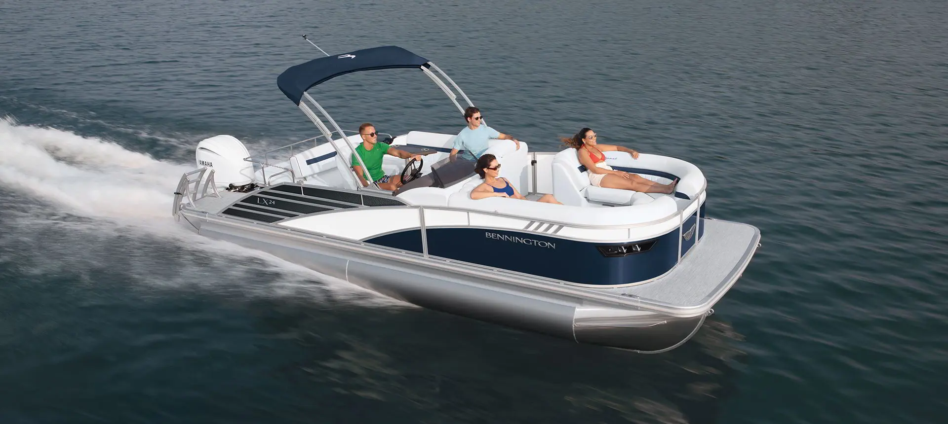 side view of a bennington LX sport pontoon boat cruising on a lake