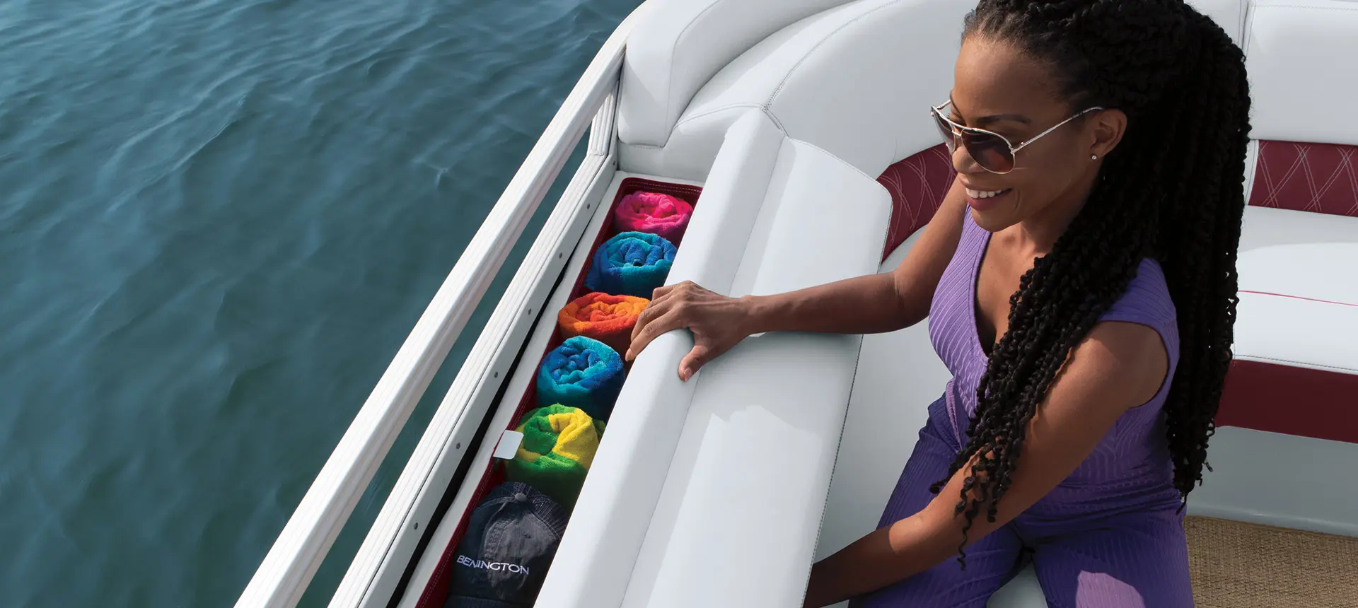 woman grabbing towels out of the integrated storage on a bennington r bowrider pontoon boat