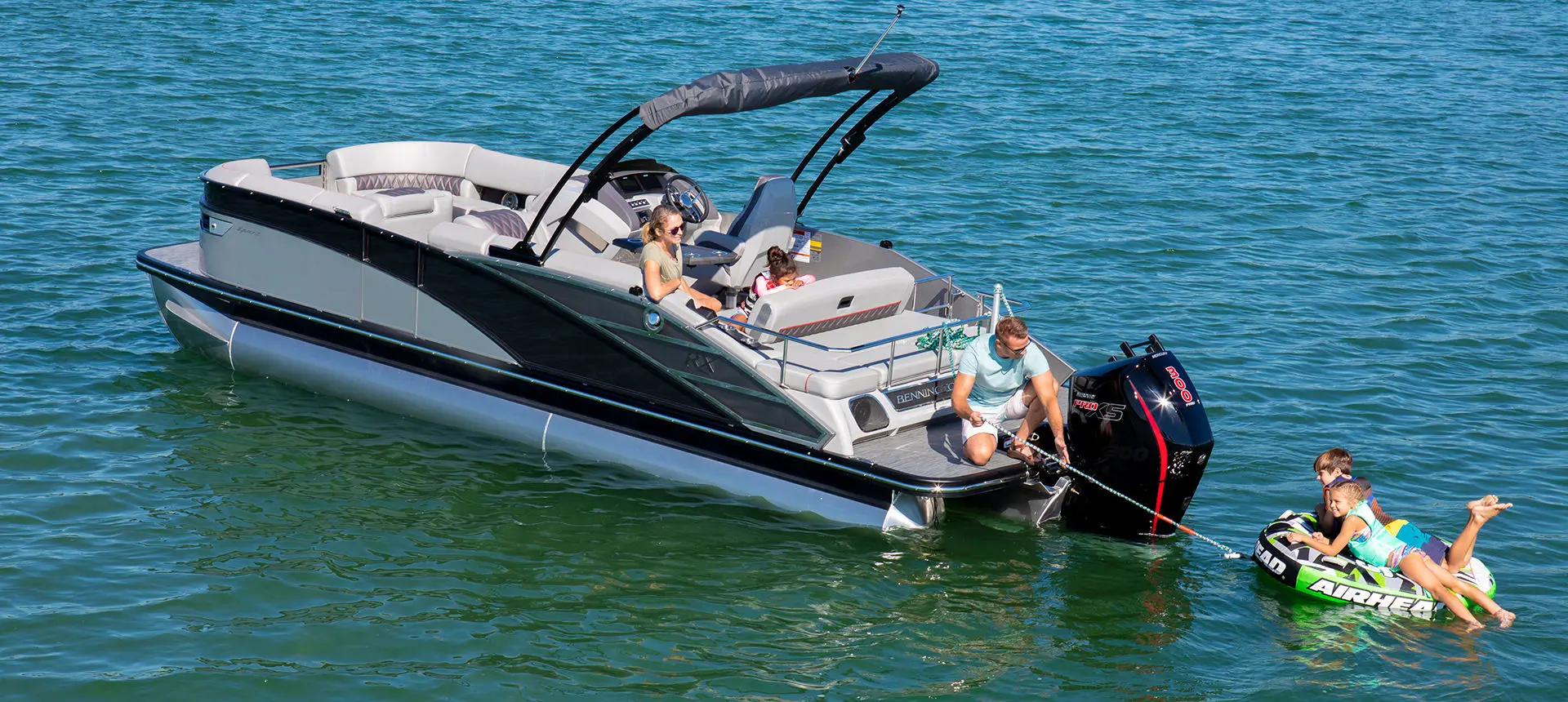 kids playing in the water with a ball in front of a bennington rx sport pontoon boat