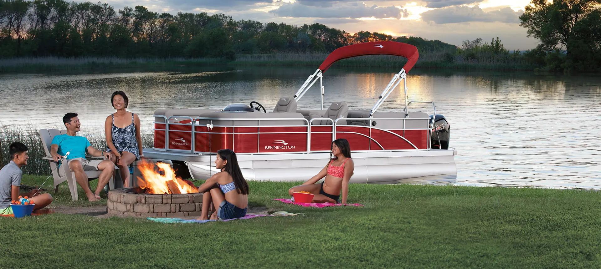 family sitting around a fire near a Bennington SV pontoon boat