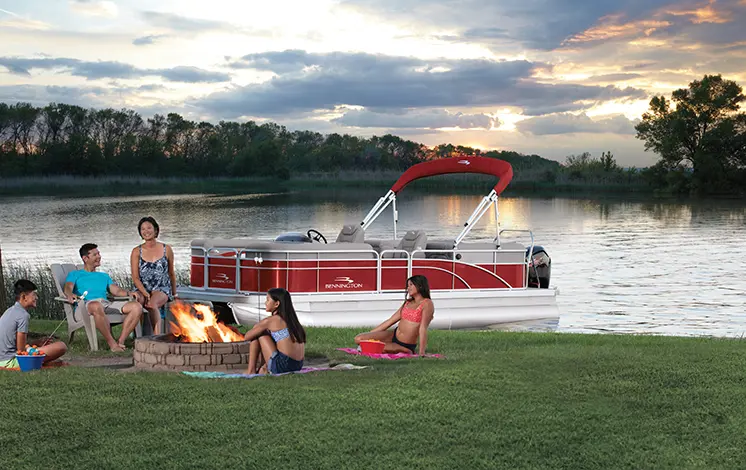 family sitting around a fire near a Bennington SV pontoon boat