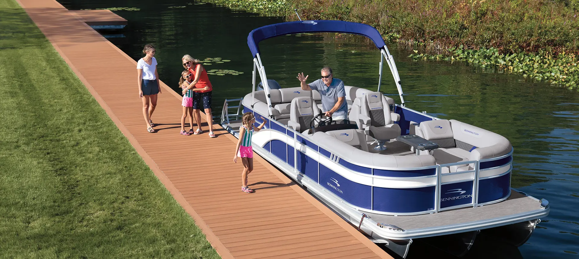 man on a bennington sx pontoon boat waving to a girl on the dock