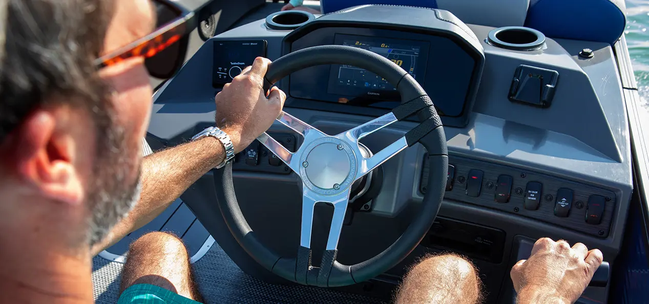 man at the helm of a Bennington S pontoon boat on a lake