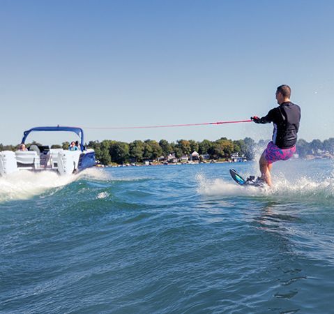 Wakeboarder being towed behind a Bennington Watersport pontoon boat. 