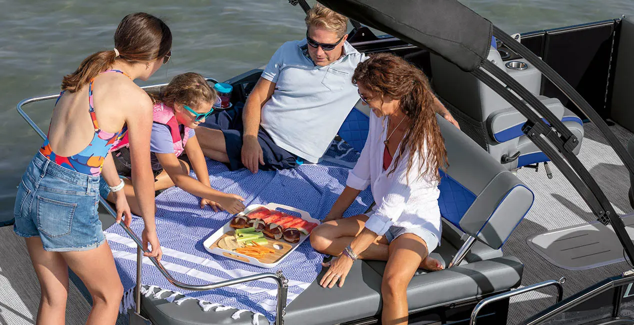 Family having a snack on the stern Swingback seat on a Bennington L Bowrider Line pontoon boat.