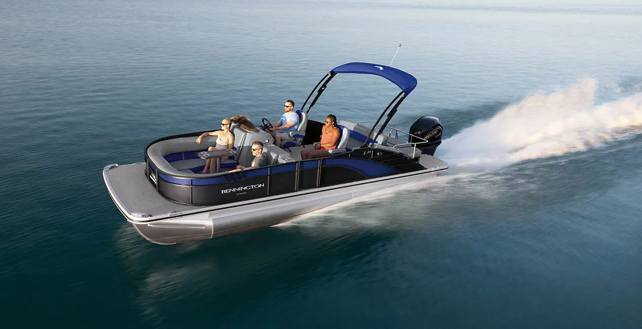Side profile of a Bennington L Bowrider Line pontoon boat cruising across a lake.