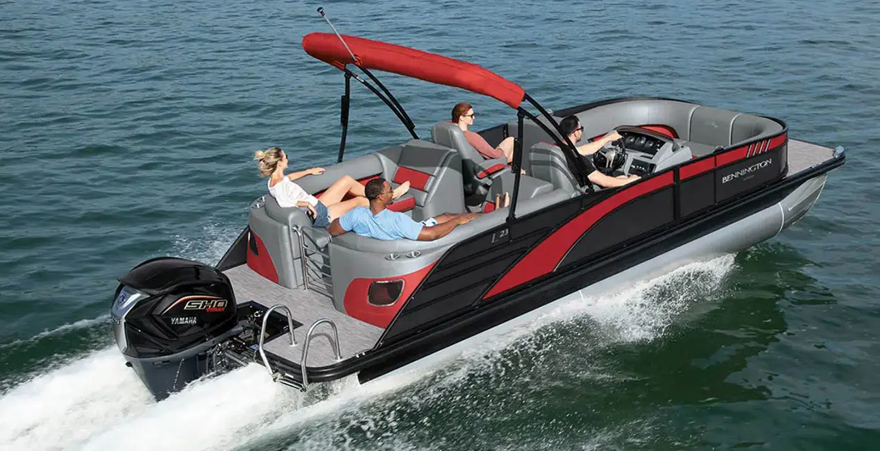 Aerial view of a Bennington L Bowrider Line pontoon boat with Quad Bench layout cruising across a lake.