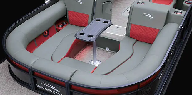Close-up of the step-down U-Lounge in gray and red with table on a Bennington L Bowrider Line pontoon boat.