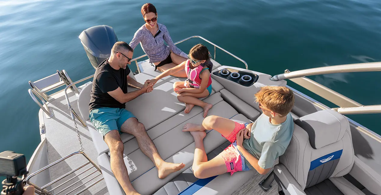 Aerial view of a family relaxing on the swingback seat on a Bennington LX Sport pontoon boat with swingback layout.