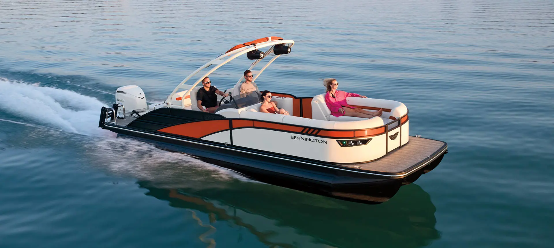 Side profile of a Bennington LX Sport pontoon boat cruising across a lake.