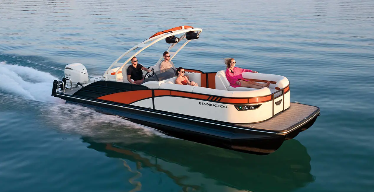 Side profile of a Bennington LX Sport pontoon boat cruising across a lake.