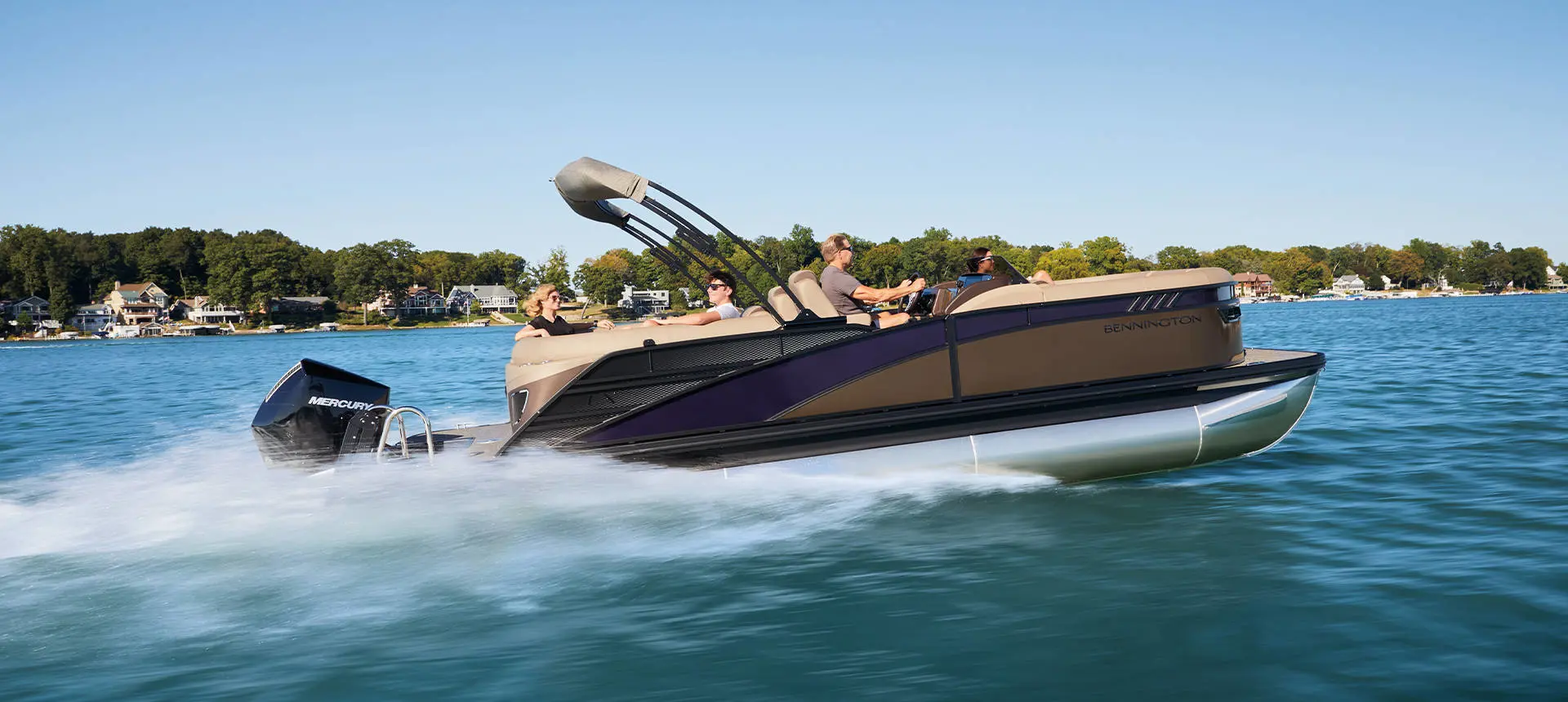A couple smiling from the bow seating on a Bennington LX Sport pontoon boat.
