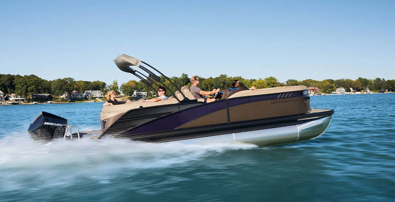 A couple smiling from the bow seating on a Bennington LX Sport pontoon boat.