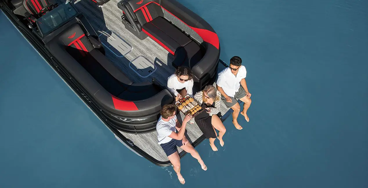4 people having a snack on the bow of a Bennington M Line pontoon boat.