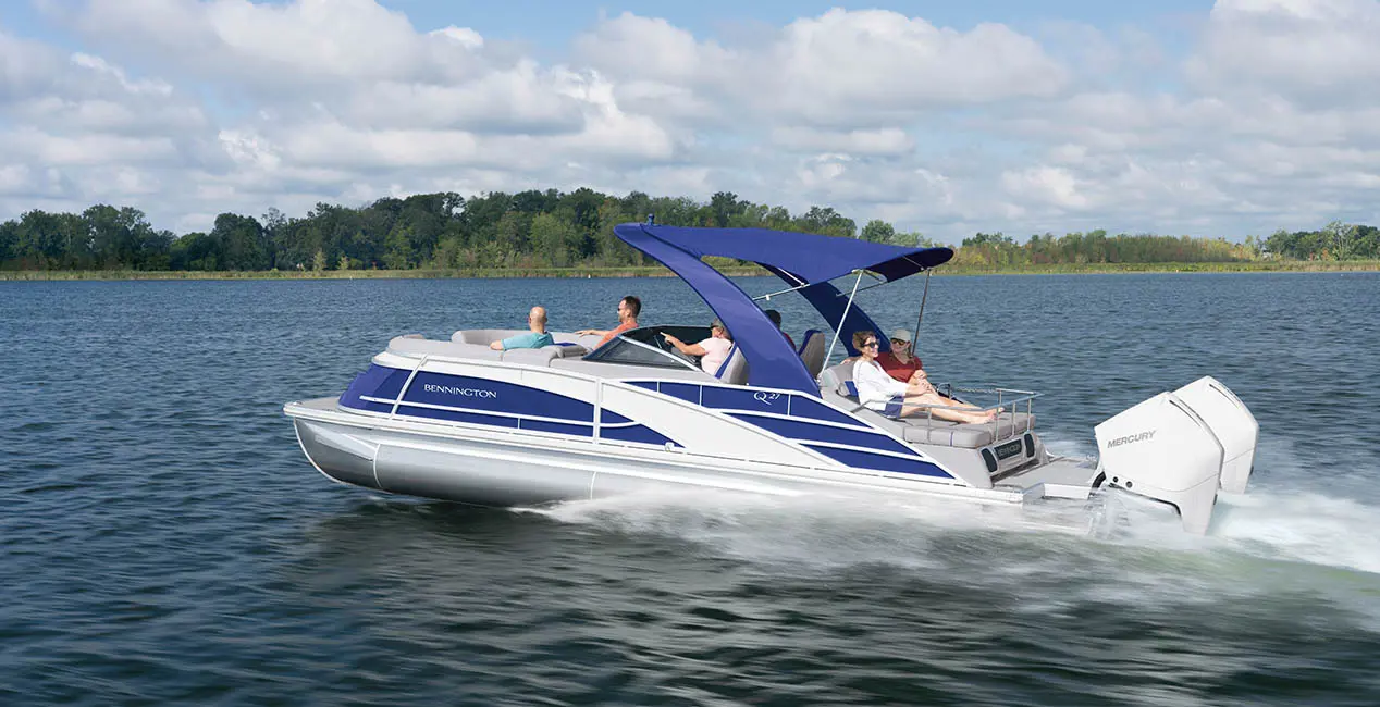 Side profile of a Bennington Q Line pontoon boat with twin engines on a lake.