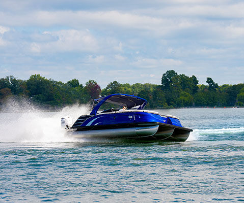 Side profile of a Bennington QX line pontoon boat cruising on a lake.