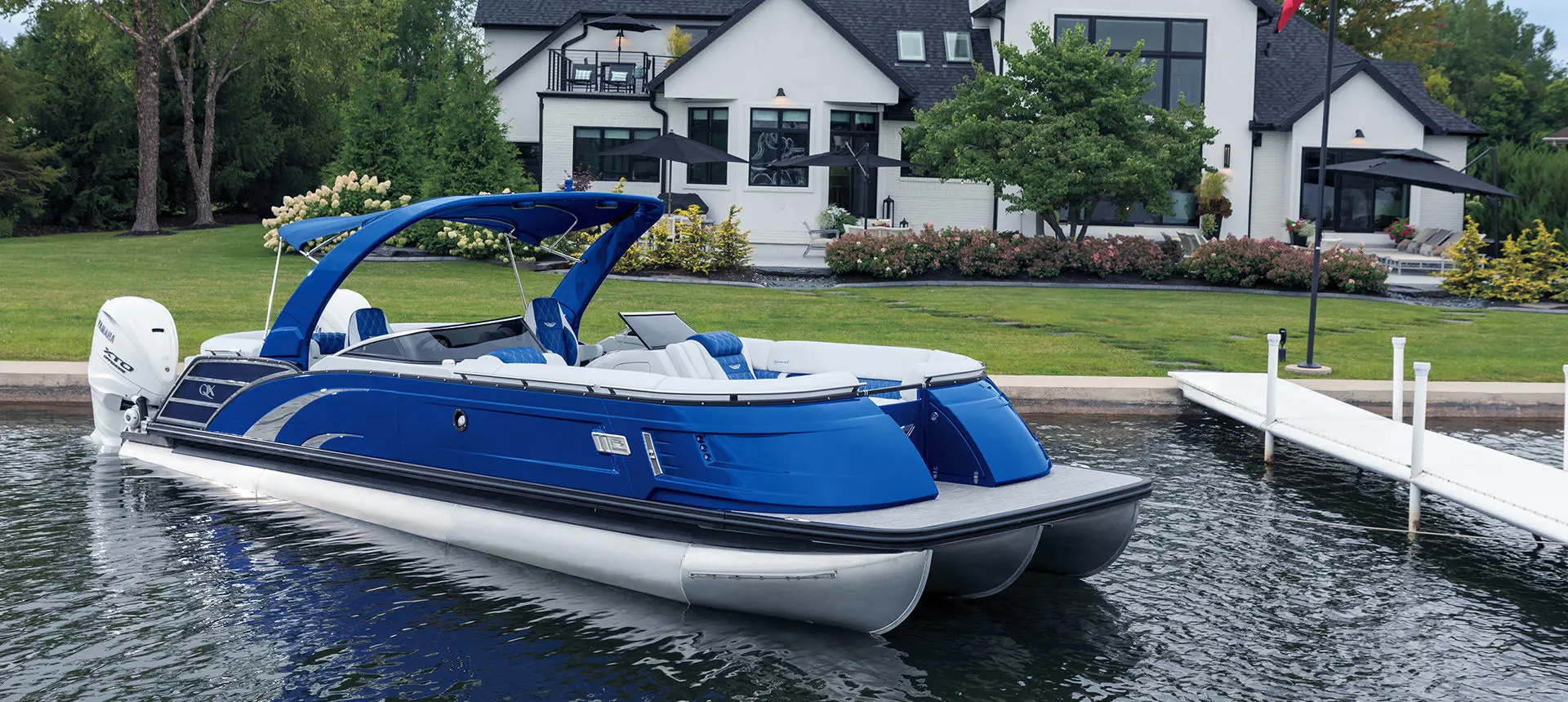 Side profile of a Bennington QX Line pontoon boat docked near shore.