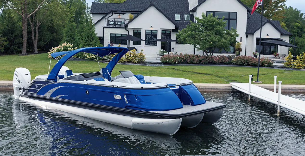 Side profile of a Bennington QX Line pontoon boat docked near shore.