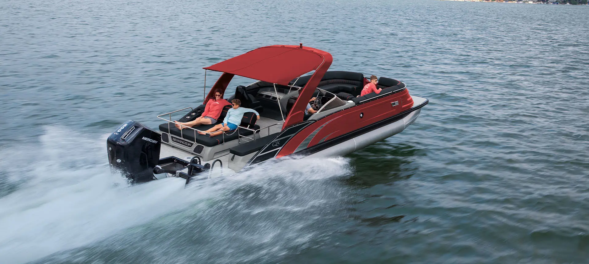 Aerial view of a Bennington QX Line pontoon boat with swingback layout cruising across a lake.