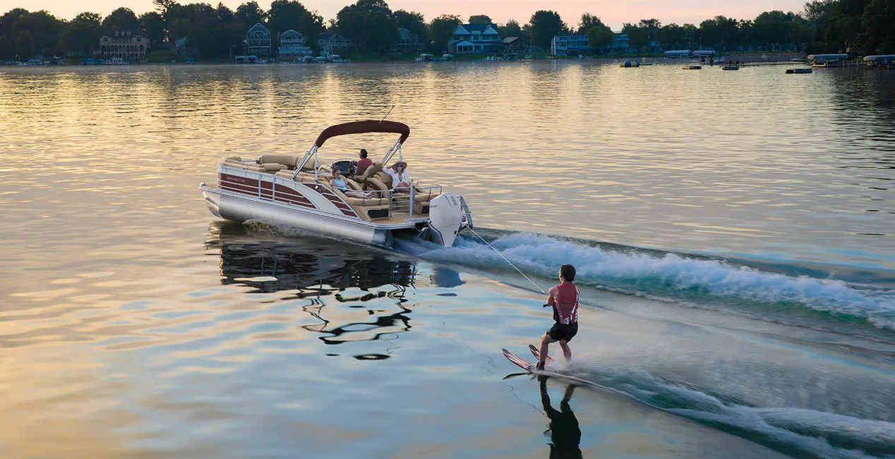 Un bateau ponton Bennington R Line tirant un skieur sur l’eau.