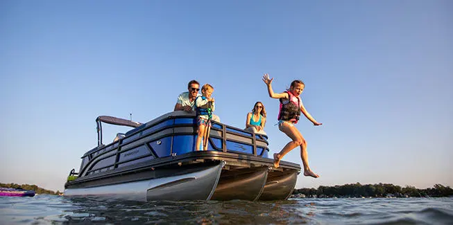 Kid jumping into the water off the stern of a Bennington S Line pontoon boat.