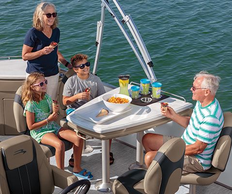 Family enjoying a meal at the port dinette on a Bennington SX Line pontoon boat.