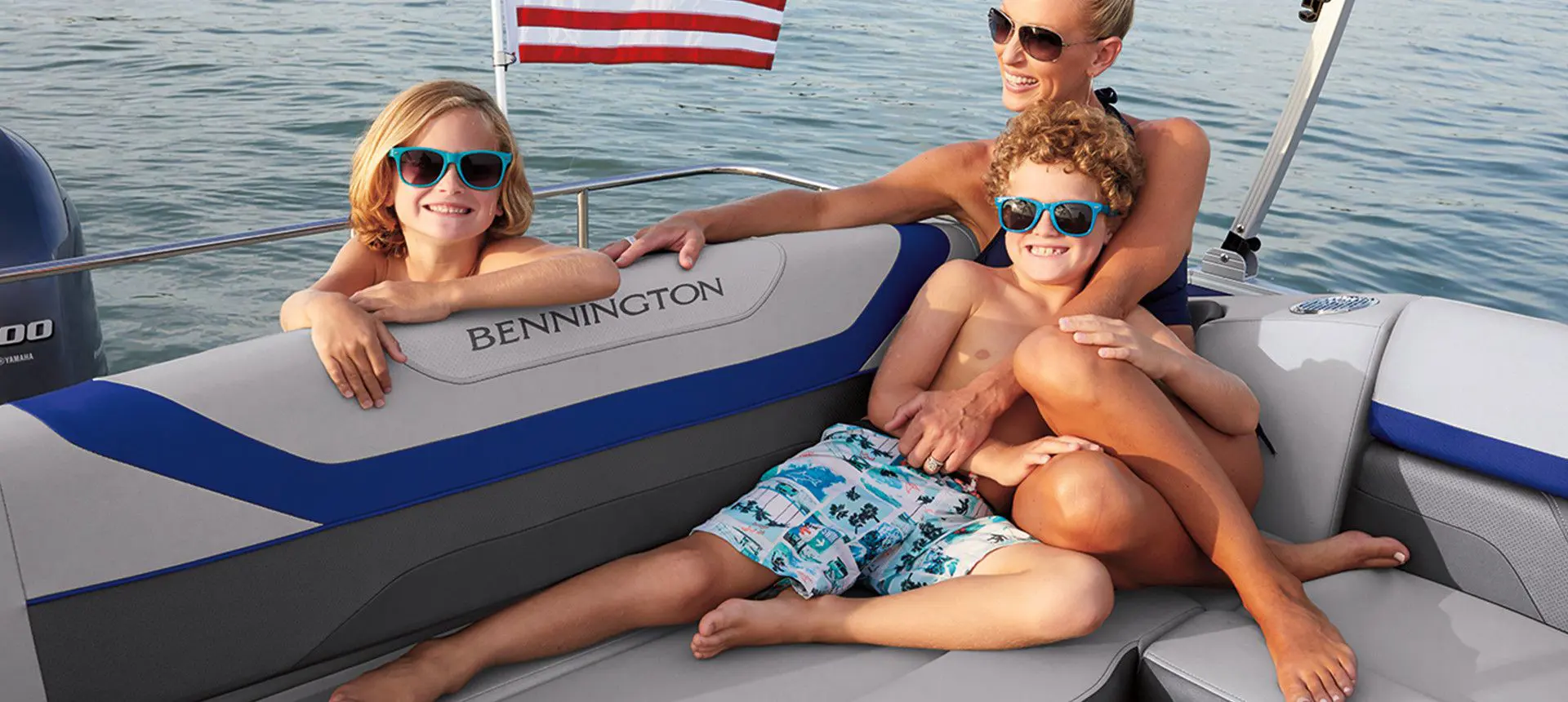 Family relaxing comfortable on the stern L-bench seat on a Bennington SX Line pontoon boat with L-Bench layout.