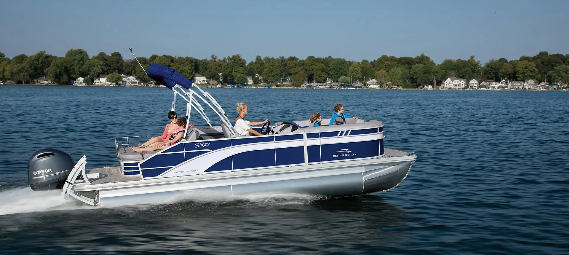 Side profile of a Bennington SX Line pontoon boat cruising on a lake.