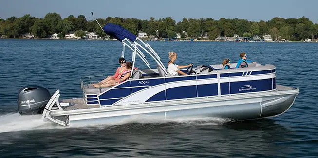 Side profile of a Bennington SX Line pontoon boat cruising on a lake.
