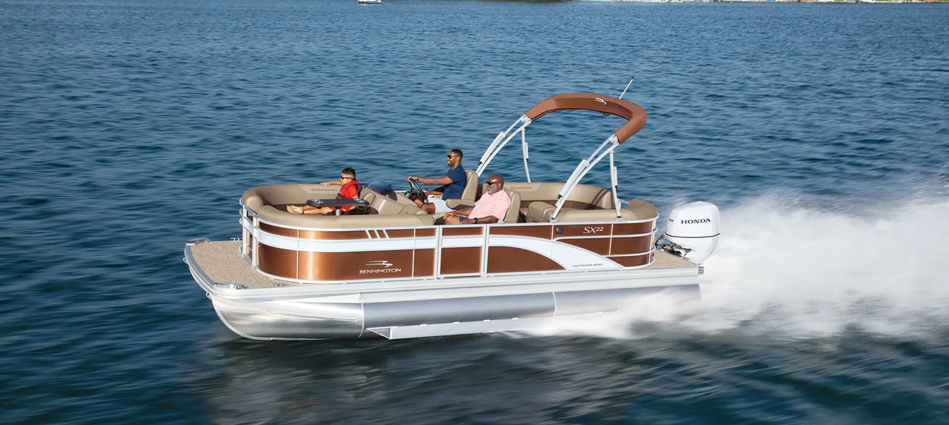 Side profile of a 22-foot Bennington SX Line pontoon boat cruising across a lake.