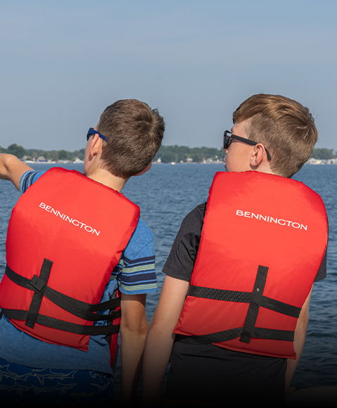2 kids wearing orange Bennington life jackets. 