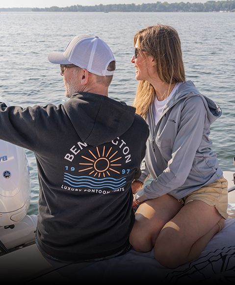 Couple points out over lake while wearing Bennington sweatshirts. 