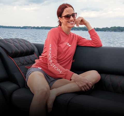 Woman smiling on back of a pontoon boat wearing a Bennington longsleeve.