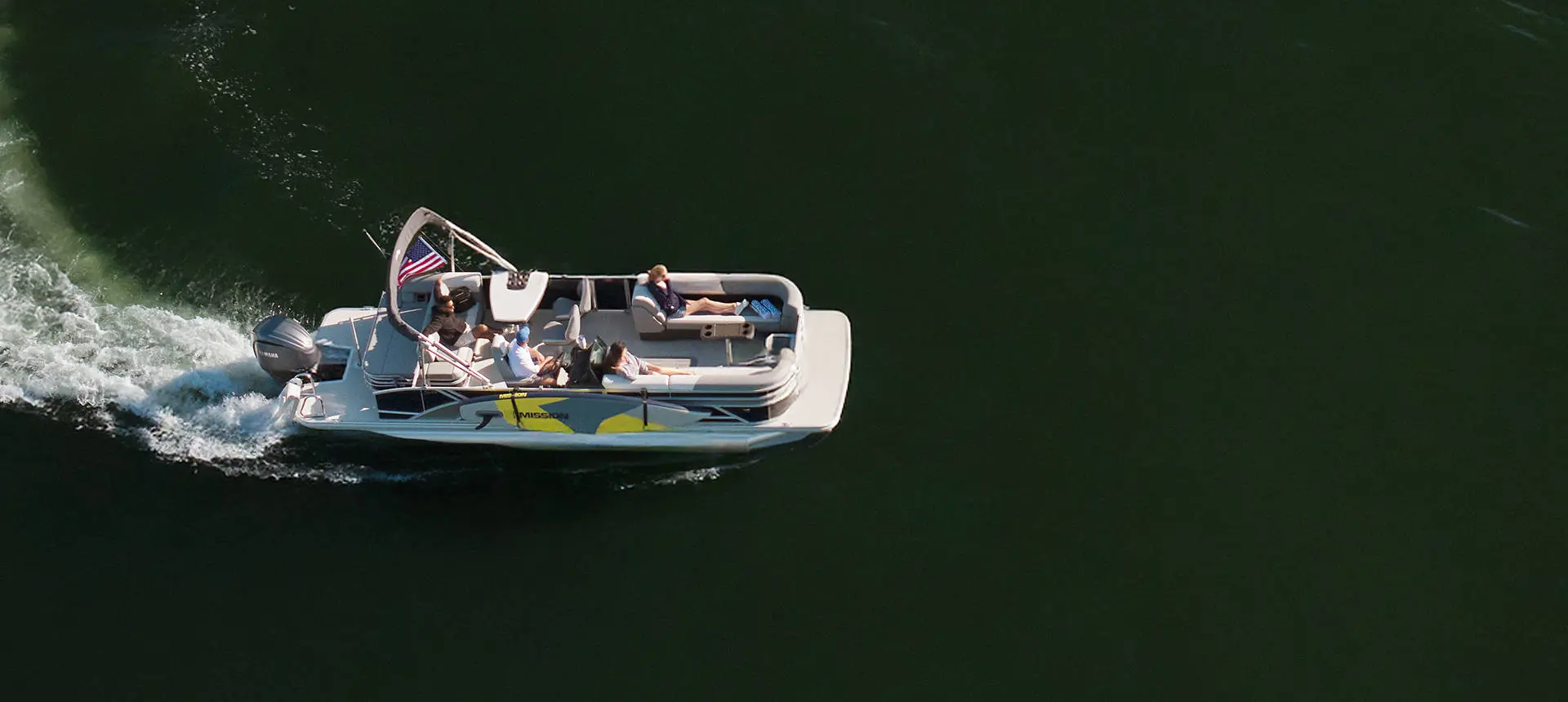 Overhead view of a pontoon boat driving, with surfboards attached using a toolless boat attachment system.