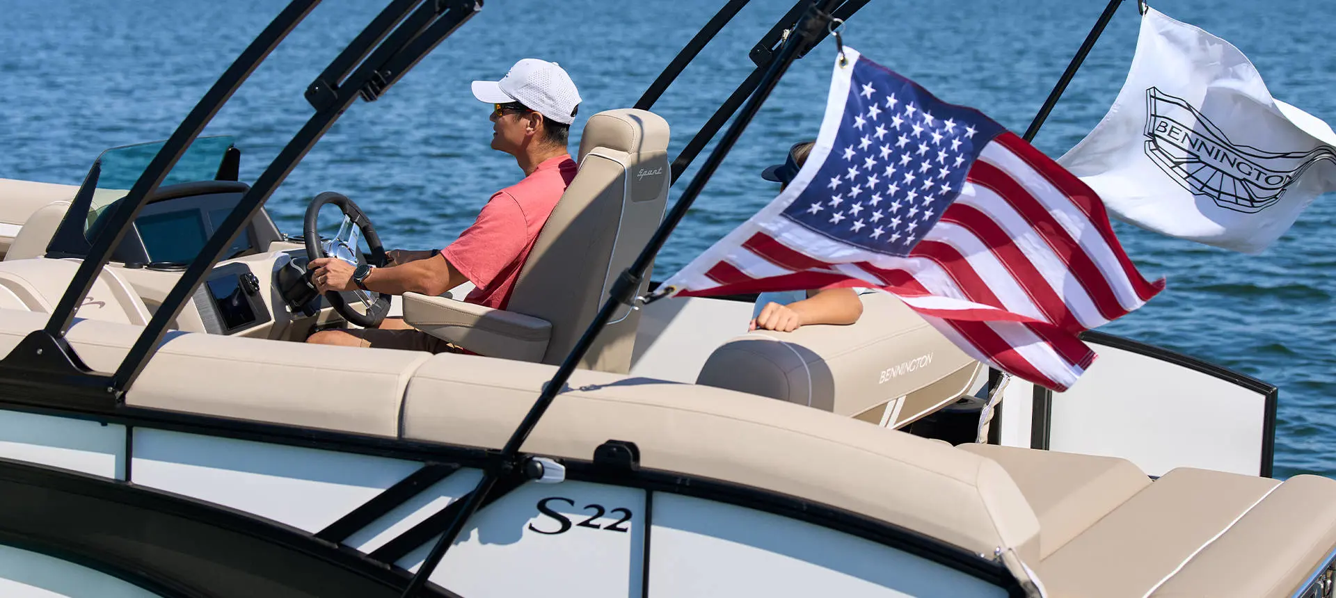 Side view of couple cruising in pontoon boat with flags attached.