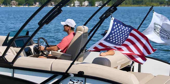 Side view of couple cruising in pontoon boat with flags attached.