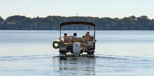 Rear view view of a pontoon boat with lily pad attached to the side using a toolless boat attachment system.