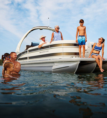 Family enjoys time in water near a parked Bennington Pontoon Boat. 