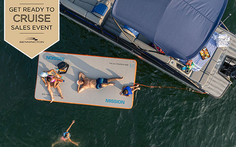 Family lounges on float pad near a parked Bennington Pontoon. Get ready to cruise sales event.