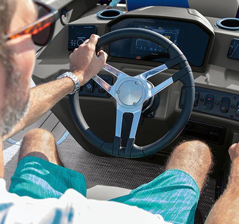 Man sitting at the captain's helm on a Bennington cruising pontoon.