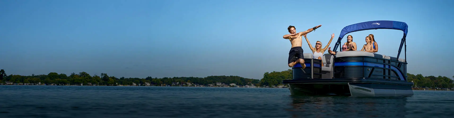 Family celebrates as boy jumps off parked pontoon in the summer. 