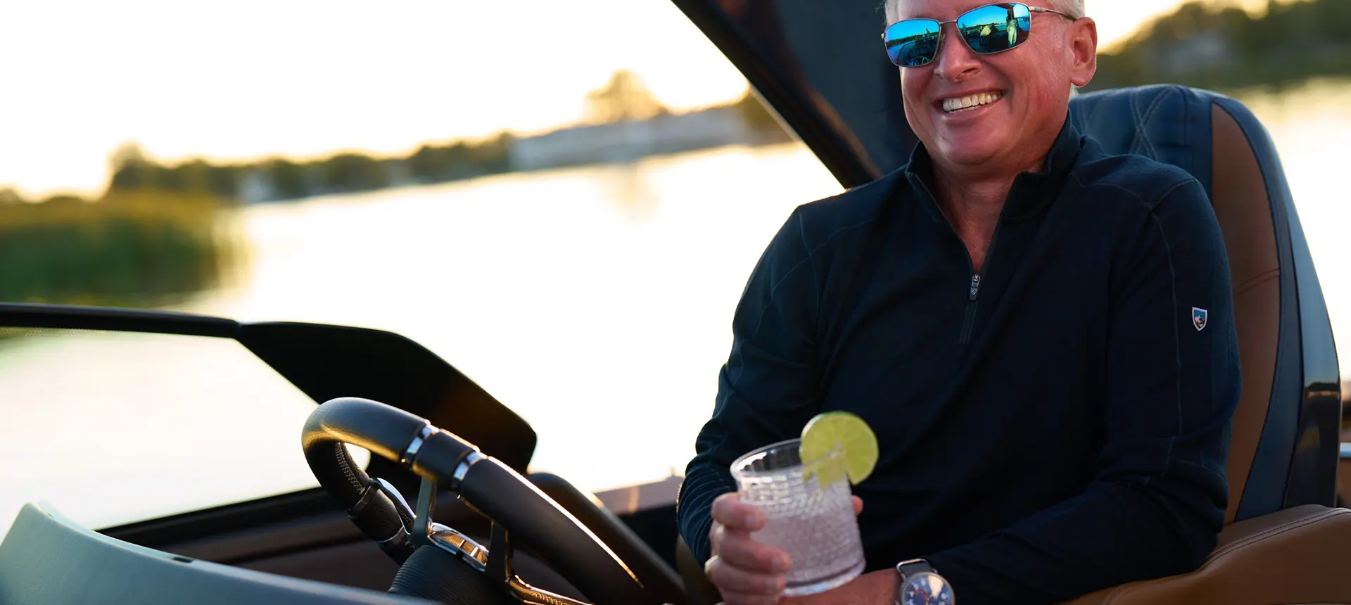 A man smiling at the helm of a Bennington QX line pontoon boat.