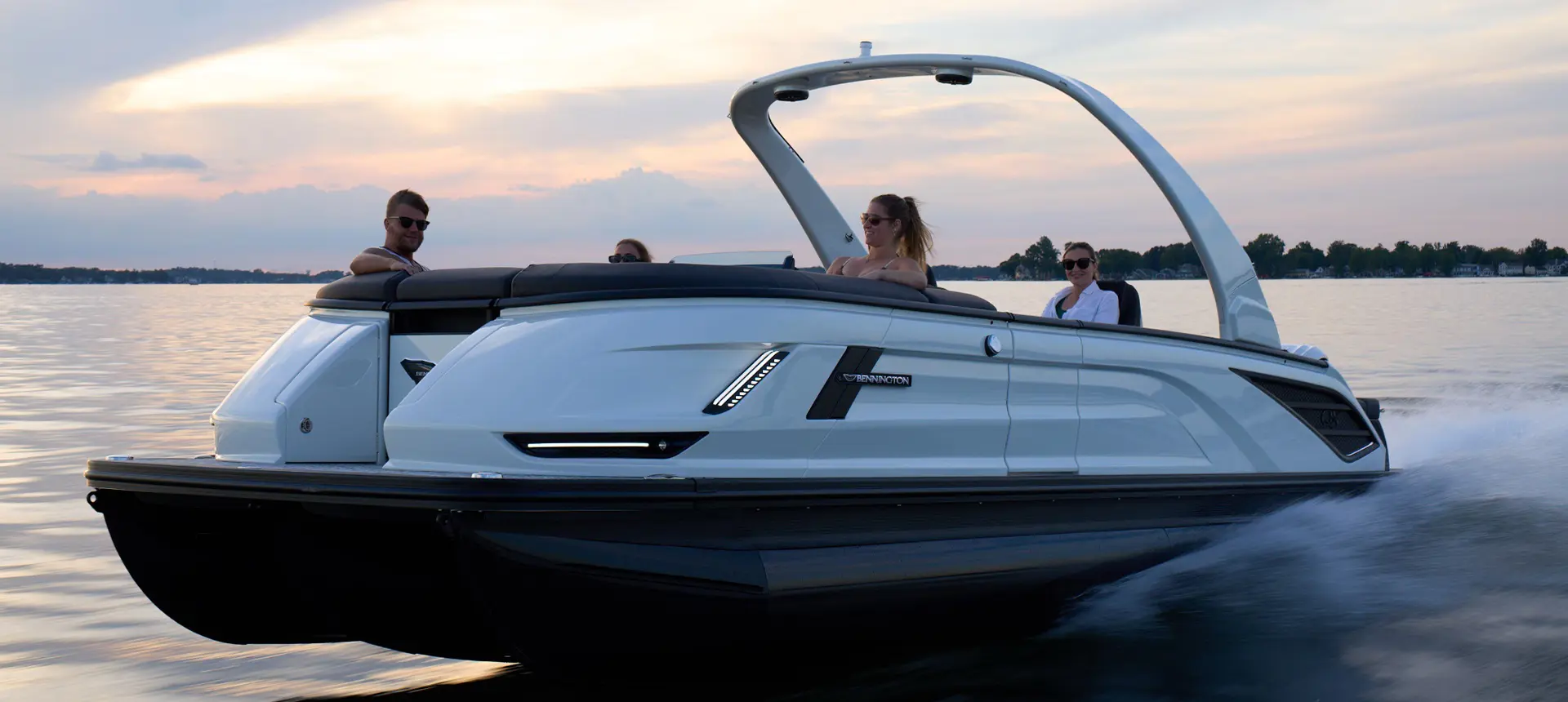 4 people enjoying a lake cruise on a Bennington QX line pontoon boat.