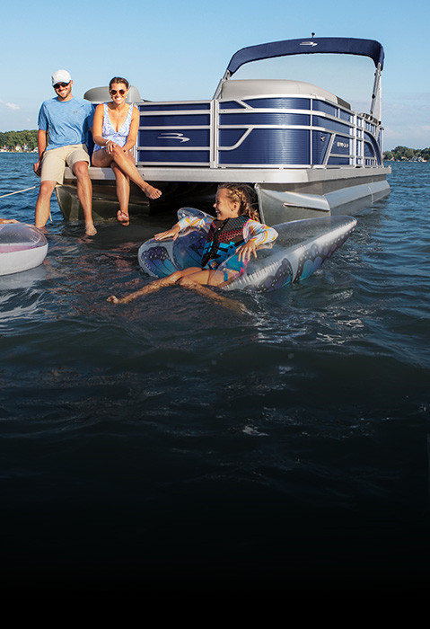 2 kids floating in the water near parents on the back of a Bennington S One Pontoon Boat. 