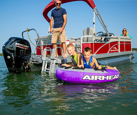 Kids tubing behind a Bennington S One Pontoon Boat with a ski tow bar attachment. 