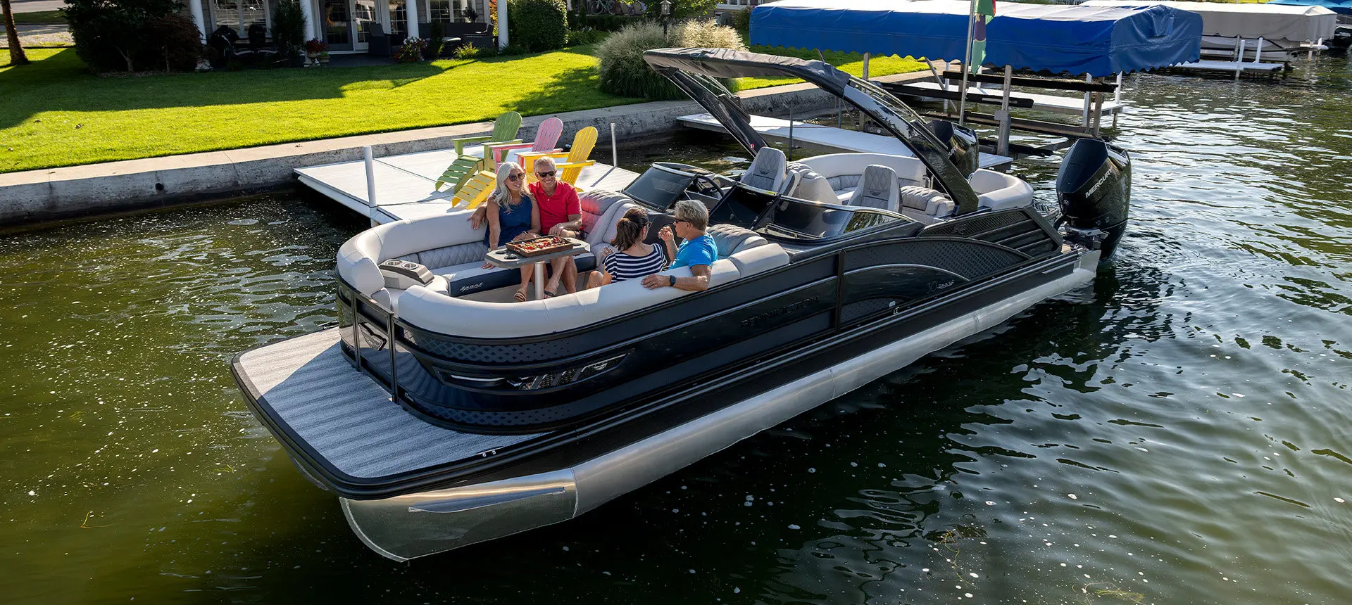 Side profile of a Bennington R Line pontoon boat cruising across a lake.
