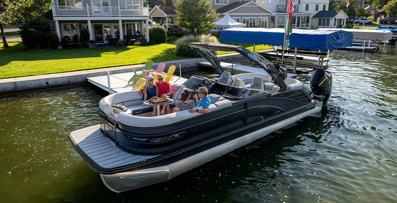 Side profile of a Bennington R Line pontoon boat cruising across a lake.
