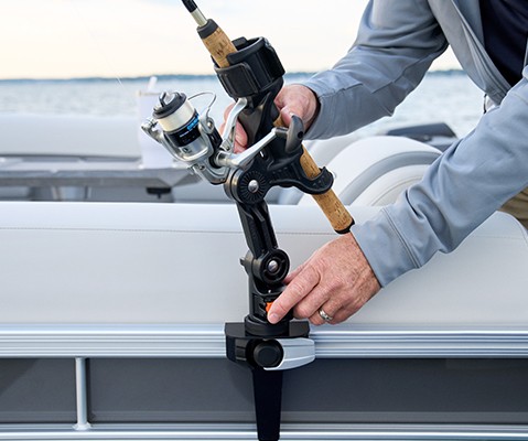 Close-up of a fishing rod being secured in an adjustable holder on a Bennington pontoon boat.