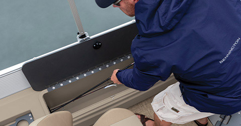 Man placing fishing pole in built-in fishing pole compartment on a Bennington pontoon.