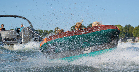 Bennington pontoon boat pulling kids on a tub with a watersports tow bar.